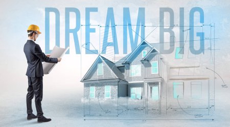 Photo for Young engineer holding blueprint with DREAM BIG inscription, house planning concept - Royalty Free Image