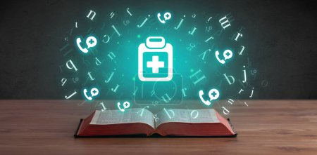 Photo for Open medical book with first aid kit icons above, global health concept - Royalty Free Image