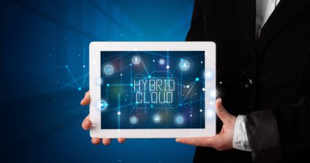 Foto de Joven empresario trabajando en tablet y muestra el cartel digital: HYBRID CLOUD - Imagen libre de derechos