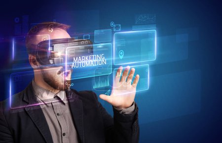 Foto de Hombre de negocios mirando a través de gafas de realidad virtual con inscripción AUTOMATIZACIÓN DE COMERCIALIZACIÓN, concepto de nueva tecnología - Imagen libre de derechos