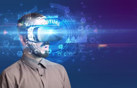 Foto de Hombre de negocios mirando a través de gafas de Realidad Virtual con inscripción VIRTUAL, concepto tecnológico innovador - Imagen libre de derechos