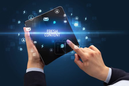 Foto de Empresario sosteniendo un smartphone plegable con inscripción CONTENIDO FRESCO, concepto de redes sociales - Imagen libre de derechos