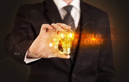 Foto de Empresario portador de bombilla con inscripción SOLAR ENERGY, Concepto de tecnología empresarial - Imagen libre de derechos