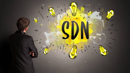 Foto de Hombre de negocios dibujo bombilla de colores con abreviatura SDN, concepto de idea de nueva tecnología - Imagen libre de derechos