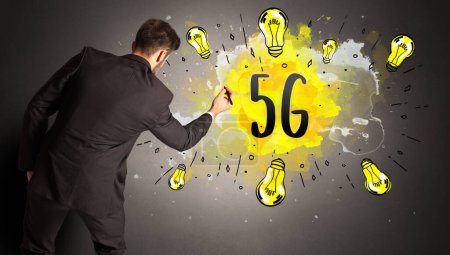 Foto de Hombre de negocios dibujo bombilla de colores con abreviatura 5G, concepto de idea de nueva tecnología - Imagen libre de derechos