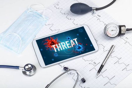 Foto de Tablet PC y herramientas médicas en superficie blanca con inscripción Amenaza, concepto pandémico - Imagen libre de derechos