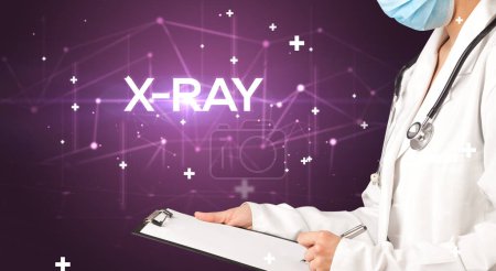 Photo for Doctor fills out medical record with X-RAY inscription, medical concept - Royalty Free Image