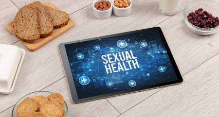 Foto de Concepto SEXUAL SALUD en la PC tableta con alimentos saludables alrededor, vista superior - Imagen libre de derechos