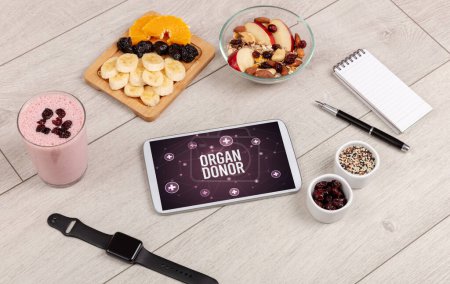 Téléchargez les photos : ORGAN DONOR concept en comprimé PC avec des aliments sains autour, vue du dessus - en image libre de droit