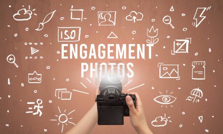 Photo for Hand taking picture with digital camera and ENGAGEMENT PHOTOS inscription, camera settings concept - Royalty Free Image