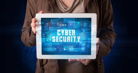 Photo for Young business person working on tablet and shows the digital sign: CYBER SECURITY - Royalty Free Image