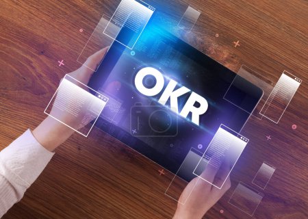 Téléchargez les photos : Gros plan d'une tablette à main avec abréviation OKR, concept de technologie moderne - en image libre de droit