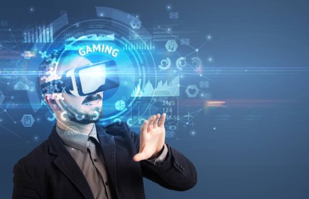 Foto de Hombre de negocios mirando a través de gafas de realidad virtual con inscripción GAMING, concepto de tecnología innovadora - Imagen libre de derechos