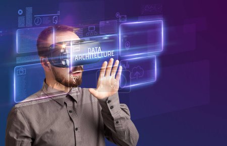 Photo for Businessman looking through Virtual Reality glasses with DATA ARCHITECTURE inscription, new technology concept - Royalty Free Image