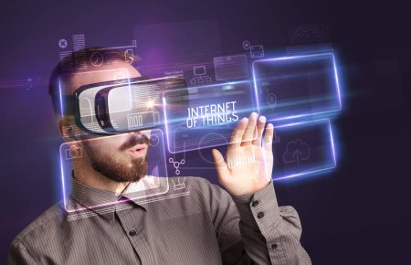 Homme d'affaires regardant à travers des lunettes de réalité virtuelle avec inscription INTERNET OF THINGS, concept de nouvelle technologie
