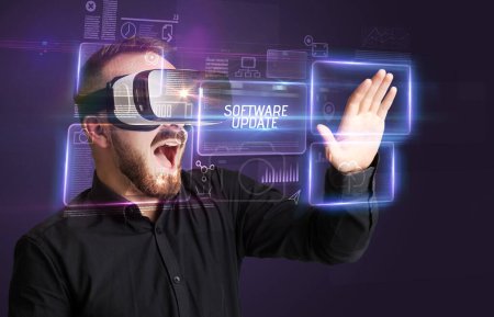 Téléchargez les photos : Homme d'affaires regardant à travers des lunettes de réalité virtuelle avec inscription LOGICIEL MISE À JOUR, concept de nouvelle technologie - en image libre de droit