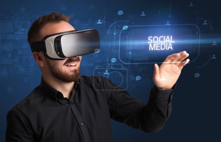 Téléchargez les photos : Homme d'affaires regardant à travers des lunettes de réalité virtuelle avec inscription MEDIA SOCIAL, concept de réseautage social - en image libre de droit
