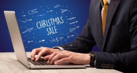 Téléchargez les photos : Homme d'affaires travaillant sur ordinateur portable avec inscription CHRISTMAS SALE, concept d'achat en ligne - en image libre de droit