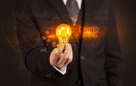 Téléchargez les photos : Homme d'affaires tenant une ampoule avec inscription CRYPTO MINING, concept de technologie d'entreprise - en image libre de droit