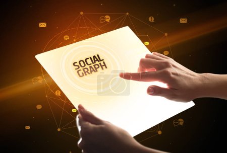 Téléchargez les photos : Tenir une tablette futuriste avec inscription SOCIAL GRAPH, concept de médias sociaux - en image libre de droit