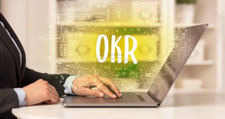 Foto de Mano trabajando en un nuevo ordenador moderno con abreviatura OKR, concepto de tecnología moderna - Imagen libre de derechos