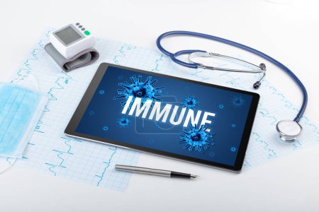 Foto de Tablet PC y herramientas médicas en superficie blanca con inscripción INMUNE, concepto pandémico - Imagen libre de derechos