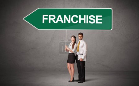 Photo for Young business person in casual holding road sign with FRANCHISE inscription, new business direction concept - Royalty Free Image