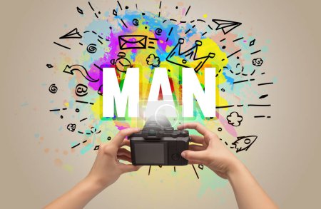 Téléchargez les photos : Gros plan d'une main tenant un appareil photo numérique avec dessin abstrait et inscription MAN - en image libre de droit