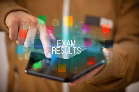 Photo for Young man holding a foldable smartphone with EXAM RESULTS inscription, educational concept - Royalty Free Image