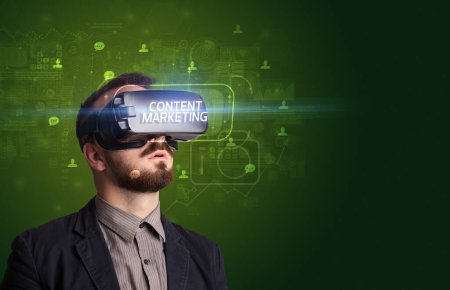 Téléchargez les photos : Homme d'affaires regardant à travers des lunettes de réalité virtuelle avec inscription CONTENT MARKETING, concept de réseautage social - en image libre de droit