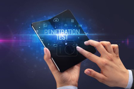 Foto de Empresario sosteniendo un smartphone plegable con inscripción PENETRATION TEST, concepto de ciberseguridad - Imagen libre de derechos
