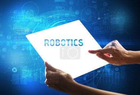 Foto de Tableta futurista Hand Holdig con inscripción ROBOTICS, concepto de nueva tecnología - Imagen libre de derechos