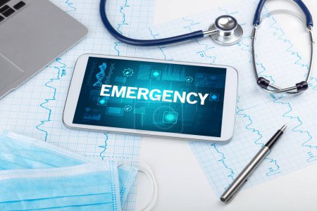 Téléchargez les photos : Tablette pc et matériel médical avec inscription d'urgence, concept de prévention - en image libre de droit