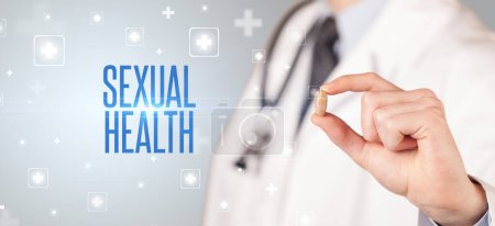 Téléchargez les photos : Gros plan d'un médecin qui donne une pilule avec inscription SEXUAL HEALTH, concept médical - en image libre de droit