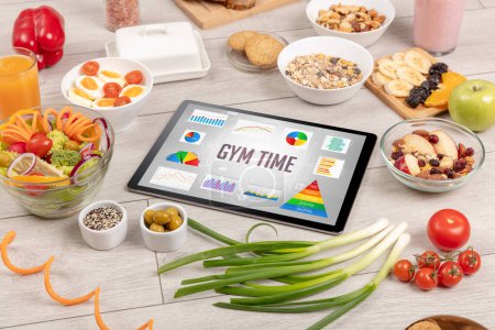 Foto de Alimento orgánico y tableta pc que muestra la inscripción GYM TIME, composición nutricional saludable - Imagen libre de derechos
