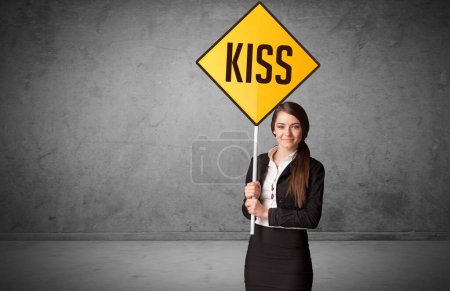 Téléchargez les photos : Jeune homme d'affaires tenant un panneau routier avec inscription KISS, nouveau concept de règles - en image libre de droit