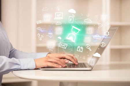 Téléchargez les photos : Homme d'affaires travaillant sur un ordinateur portable avec des icônes en verre de sable qui en sortent, concept d'entreprise en pleine croissance - en image libre de droit
