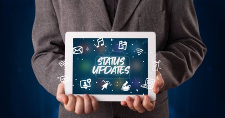 Photo for Young business person working on tablet and shows the inscription: STATUS UPDATES - Royalty Free Image