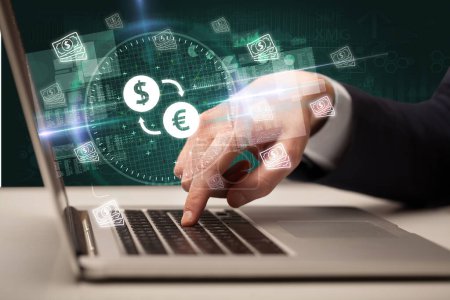 Téléchargez les photos : Main d'œuvre d'affaires travaillant en bourse avec dollar - icônes de la bourse de l'euro sortant de l'écran d'ordinateur portable - en image libre de droit