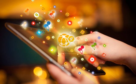 Foto de Primer plano de una mano usando tableta con coloridos iconos de notificaciones que salen de ella, concepto de redes sociales - Imagen libre de derechos