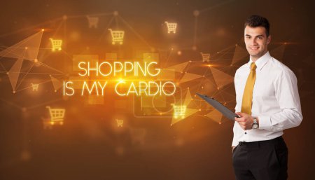 Photo for Businessman with shopping cart icons and SHOPPING IS MY CARDIO inscription, online shopping concept - Royalty Free Image