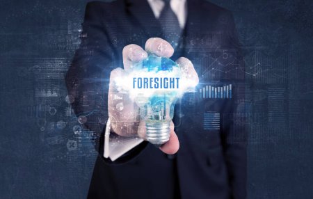 Photo for Businessman holding a light bulb with FORESIGHT inscription, new business concept - Royalty Free Image