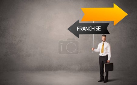 Photo for Young business person in casual holding road sign with FRANCHISE inscription, business direction concept - Royalty Free Image