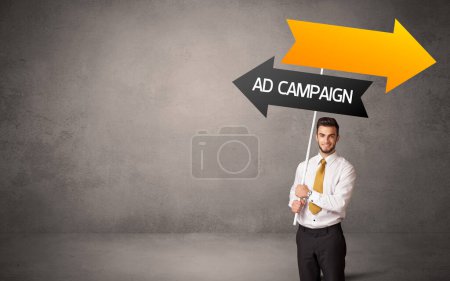 Photo for Young business person in casual holding road sign with AD CAMPAIGN inscription, business direction concept - Royalty Free Image