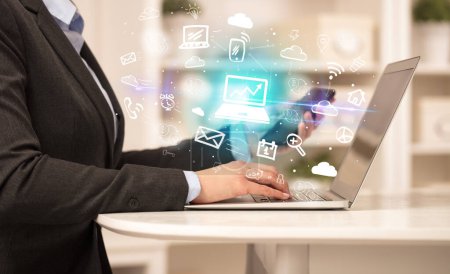 Téléchargez les photos : Homme d'affaires travaillant sur un ordinateur portable avec des icônes d'ordinateur portable qui en sortent, concept d'entreprise en pleine croissance - en image libre de droit