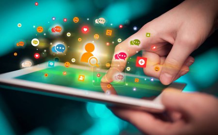 Foto de Primer plano de una mano usando tableta con coloridos iconos de búsqueda de personas que salen de ella, concepto de redes sociales - Imagen libre de derechos