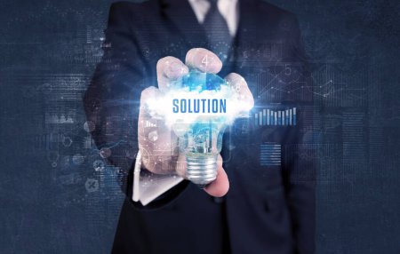 Téléchargez les photos : Homme d'affaires tenant une ampoule avec inscription SOLUTION, nouveau concept d'entreprise - en image libre de droit