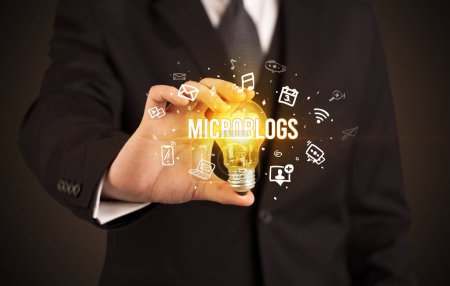 Téléchargez les photos : Homme d'affaires tenant une ampoule avec inscription MICROBLOGS, concept de médias sociaux - en image libre de droit