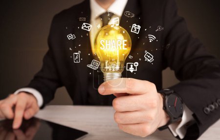 Téléchargez les photos : Homme d'affaires tenant une ampoule avec inscription SHARE, concept de médias sociaux - en image libre de droit