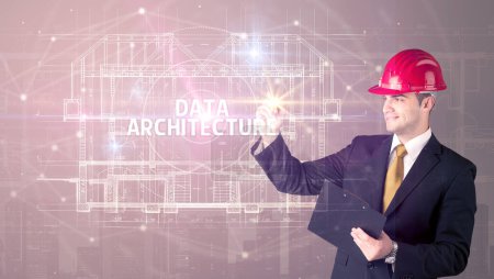 Foto de Arquitecto guapo con dibujo de casco ARQUITECTURA DE DATOS inscripción, concepto de nueva tecnología - Imagen libre de derechos